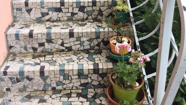 A set of outdoor stairs with mosaic tiles, surrounded by potted plants and a metal railing. - Maison Corisande, near the entrance to Bagnères de Bigorre (Gerde)