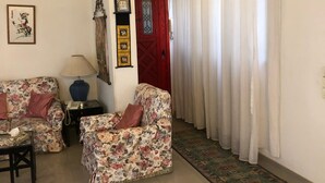 A living room with two floral sofas, a small table with a lamp, a telephone, and a red door with a glass panel. - Very cozy and comfortable in a quite place (Heliopolis)