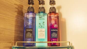Three bottles of Episode hair care products on a glass shelf.