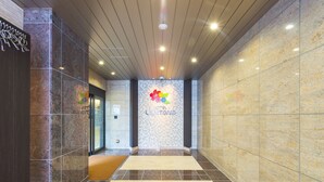 A hotel lobby with a tiled floor, a reception desk, and a wall-mounted sign.