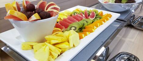 A buffet with a variety of fruits and a bowl of mixed fruits.