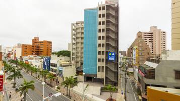 A cityscape with a prominent blue building, palm trees lining the streets, and various commercial establishments.