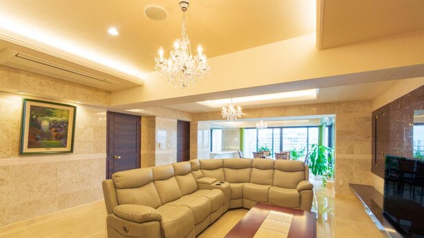 A modern living room with a sectional sofa, a wooden coffee table, and a chandelier.