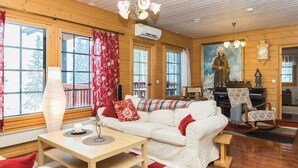 A cozy cabin interior with a white sofa, a wooden table, and a checkered floor.