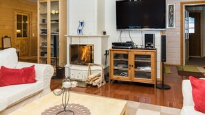A cozy living room with a fireplace, a television, and a bookshelf.