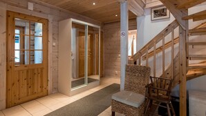 A wooden interior with a chair, a staircase, and a door leading to a room.