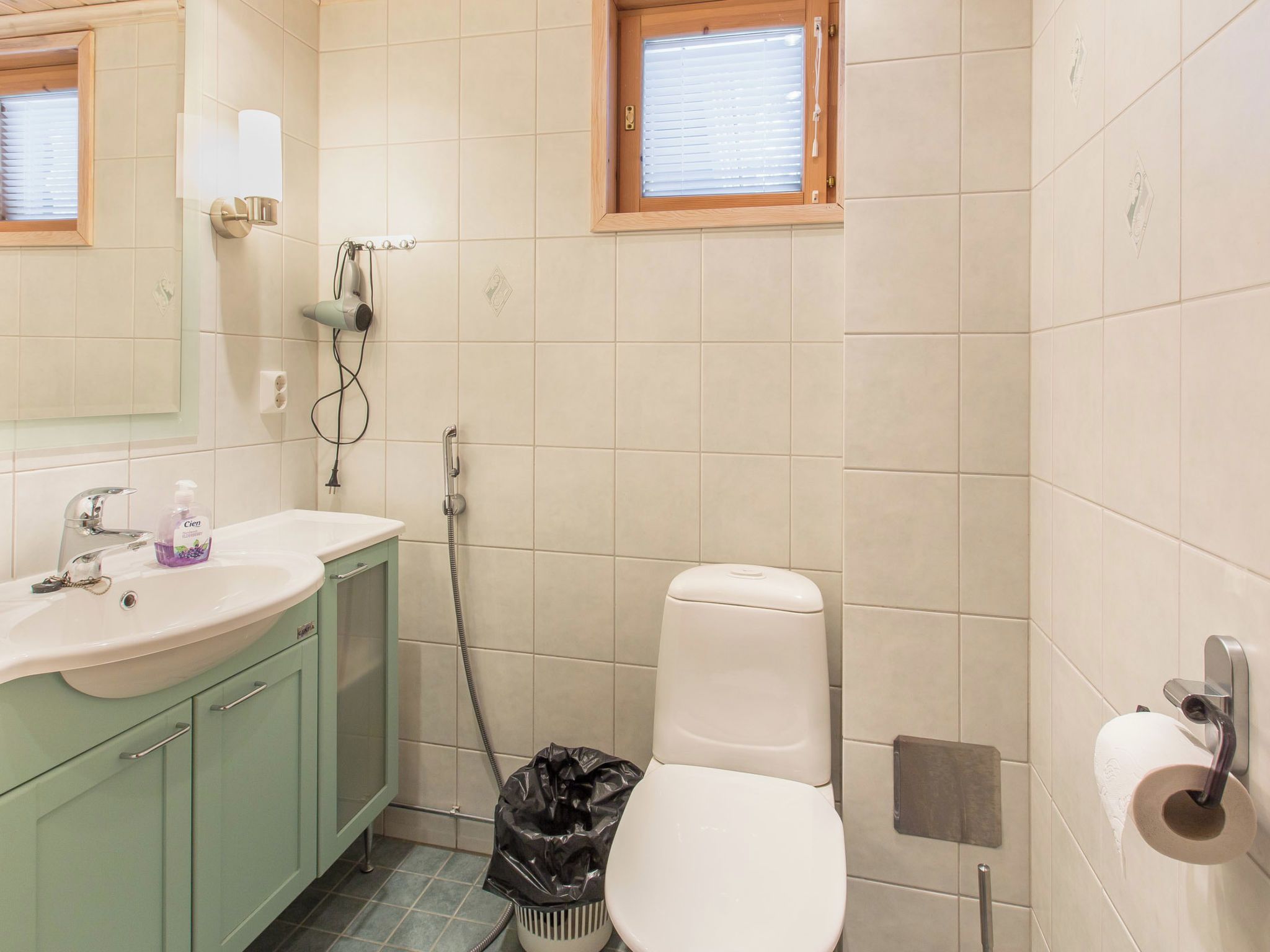 Un bagno con lavandino, specchio, water e finestra.