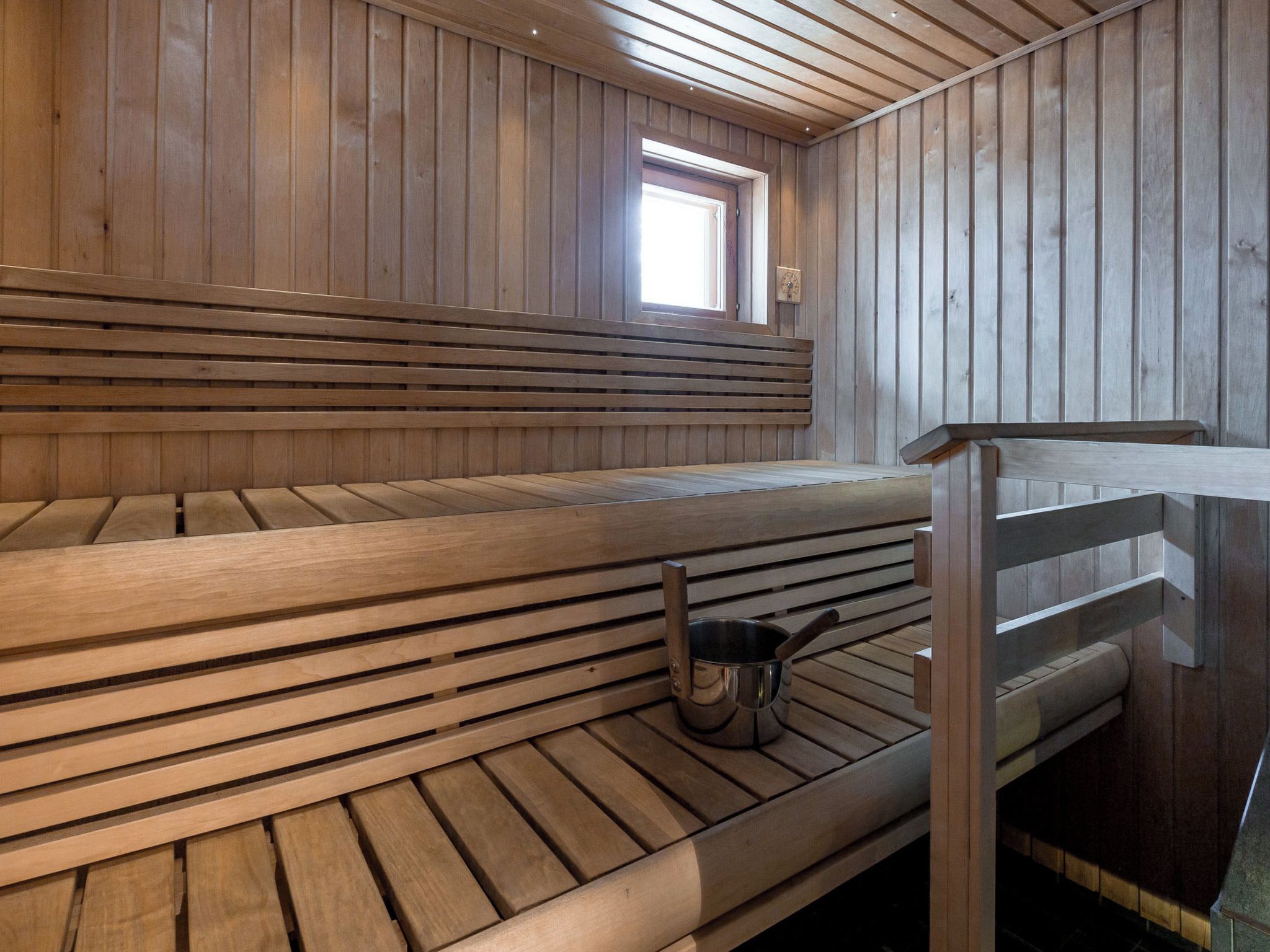Uma sauna com bancos de madeira e uma pequena janela.