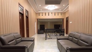 Un vestíbulo de hotel con dos sofás de cuero, una araña y una escalera que sube a otro piso.