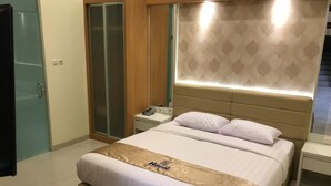 Una habitación de hotel con cama, mesitas de noche, un armario y un espejo.