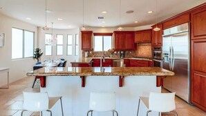 Una cocina moderna con encimeras de granito, electrodomésticos de acero inoxidable y armarios de madera.