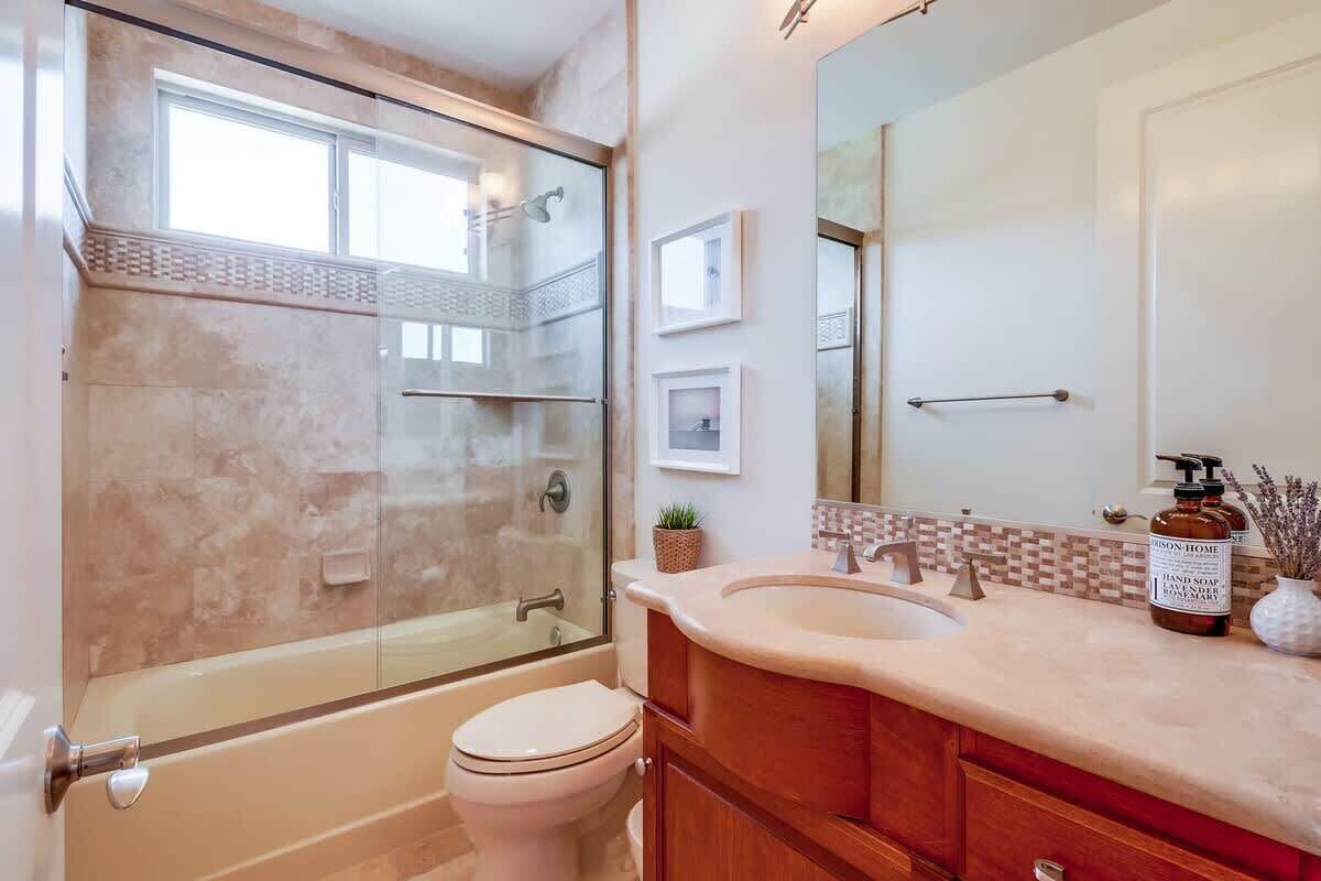 Une salle de bain avec une douche à parois de verre, des toilettes, un lavabo avec un meuble-vasque et un miroir.