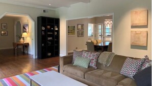 Ein Wohnzimmer mit einem beigefarbenen Sofa, einem Streifenmuster-Teppich und einem Bücherregal.