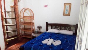 A bedroom with a bed, a wooden ladder, a shelf, and a framed picture on the wall. - La Posada del Cucú (Salento)
