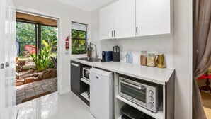 A compact kitchen with white cabinets, a built-in oven, and a small refrigerator.