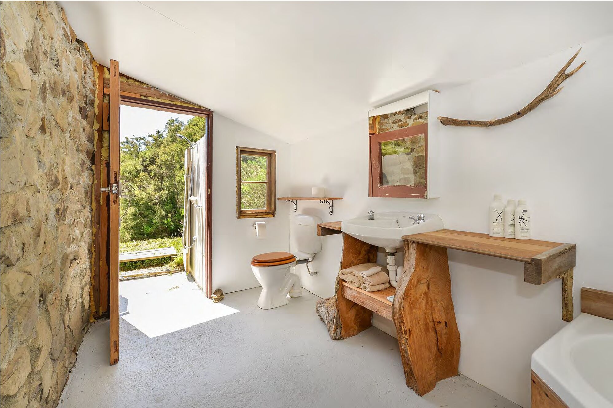 Un baño de diseño rústico, con un tocador de madera, un inodoro blanco y un espejo grande.