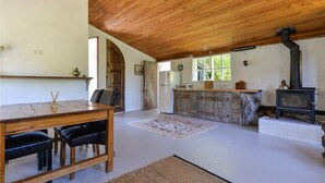 Eine rustikale Küche mit Holzbalken, einem Steinkamin und einem Essbereich mit Tisch und Stühlen.