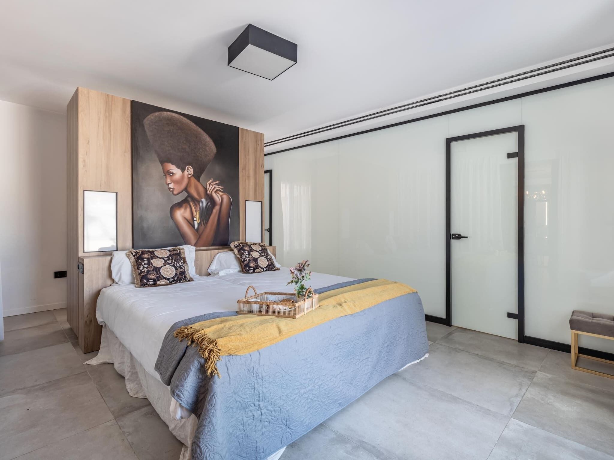 Ein modernes Schlafzimmer mit einem großen Bett, einem Gemälde an der Wand und einem Kleiderschrank.
