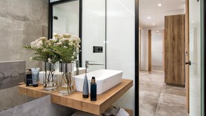 Un baño moderno con un espejo grande, lavabo blanco y estantes de madera.