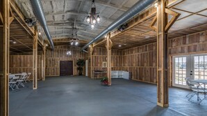 A spacious indoor area with wooden walls, a concrete floor, and a door leading to another room.