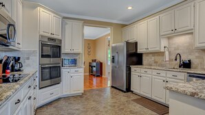 A modern kitchen with white cabinets, stainless steel appliances, and a herringbone tile floor.