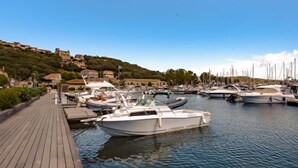Un port de plaisance avec des bateaux amarrés, une passerelle en bois et des bâtiments en arrière-plan.