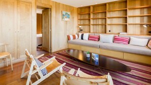 Un salon chaleureux avec un canapé, des étagères en bois et un tapis à rayures.