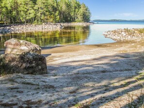 Escape to a serene lakeside haven surrounded by lush trees and a sandy shoreline.
