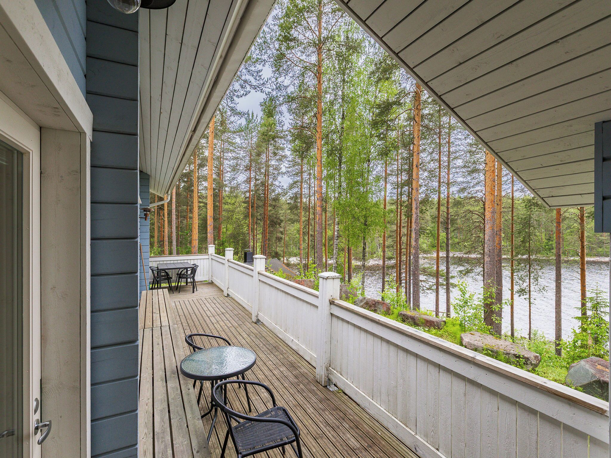 A covered deck with a view of a lake and trees.