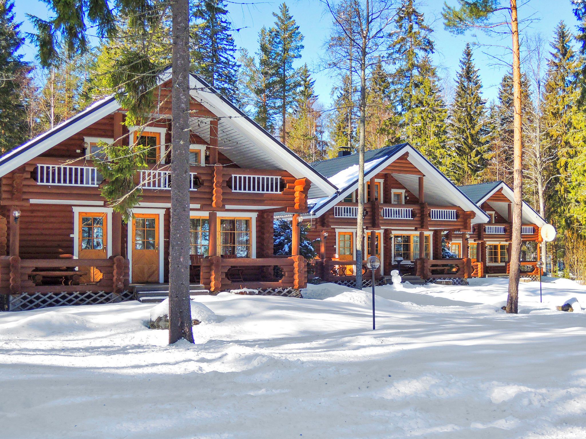 A log cabin resort with multiple buildings, each featuring a porch and a large window.