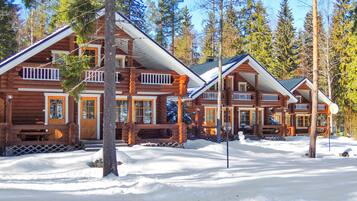 A log cabin resort with multiple buildings, each featuring a porch and a large window.