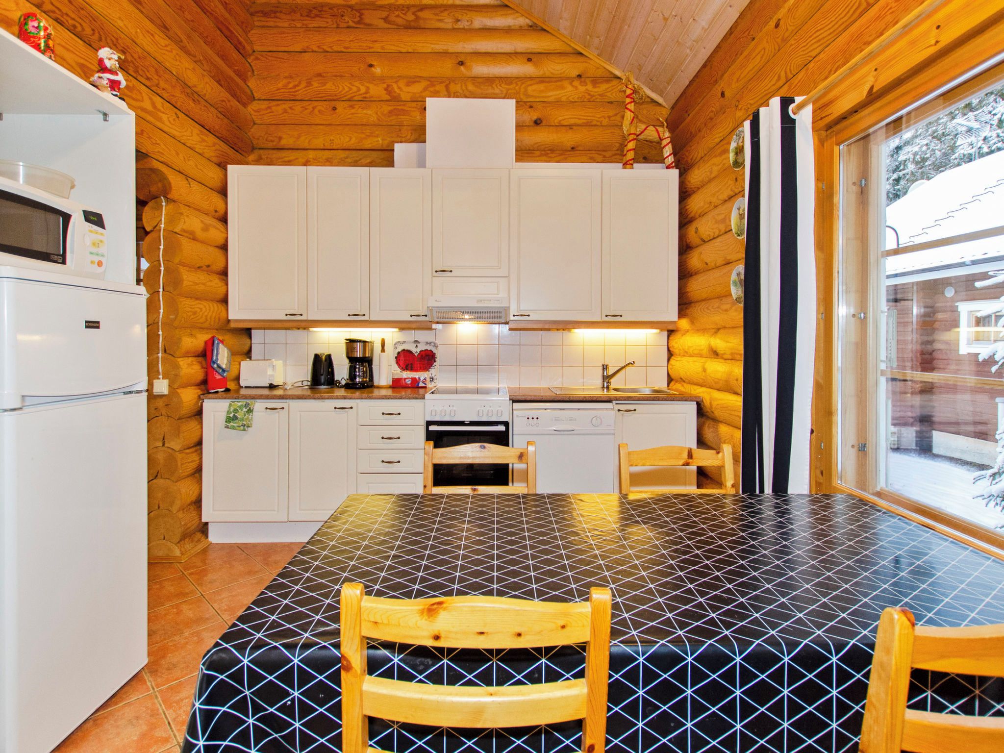 Une cuisine avec des meubles de rangement en bois, une cuisinière, un évier et une table à manger avec des chaises.