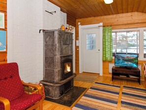 Een gezellige woonkamer met een open haard, een televisie en een rode fauteuil.