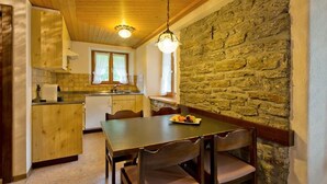 Une cuisine rustique avec des meubles en bois, un mur en pierre et une table à manger entourée de chaises.