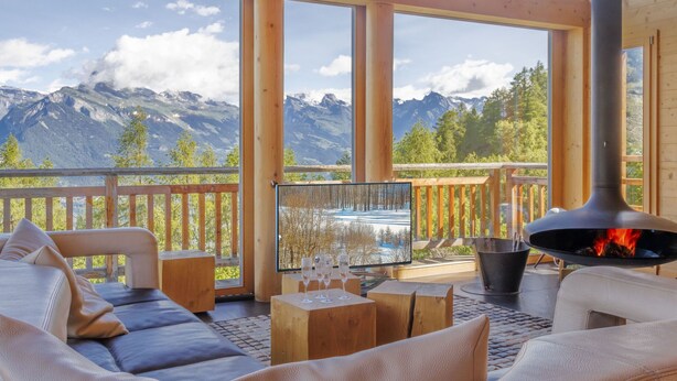 A wooden deck with a sofa, a table with glasses, and a wood stove. - Woovim 8 by Interhome (Nendaz)