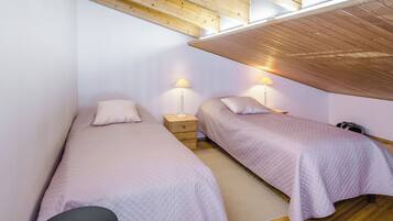 Ein Schlafzimmer mit zwei Einzelbetten, einem Nachttisch, einer Lampe und einem Sessel.