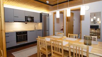 Eine moderne Küche mit grauen Schränken, Edelstahlgeräten und einem Holzespeisetisch mit Stühlen.