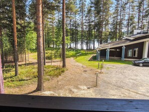 A forested area with a gravel path leading to a building with a sloped roof.