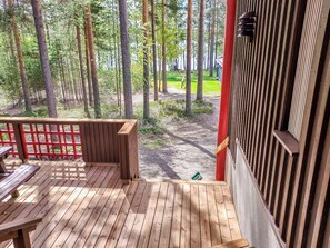 A wooden deck with benches and a red fence, overlooking a forested area.