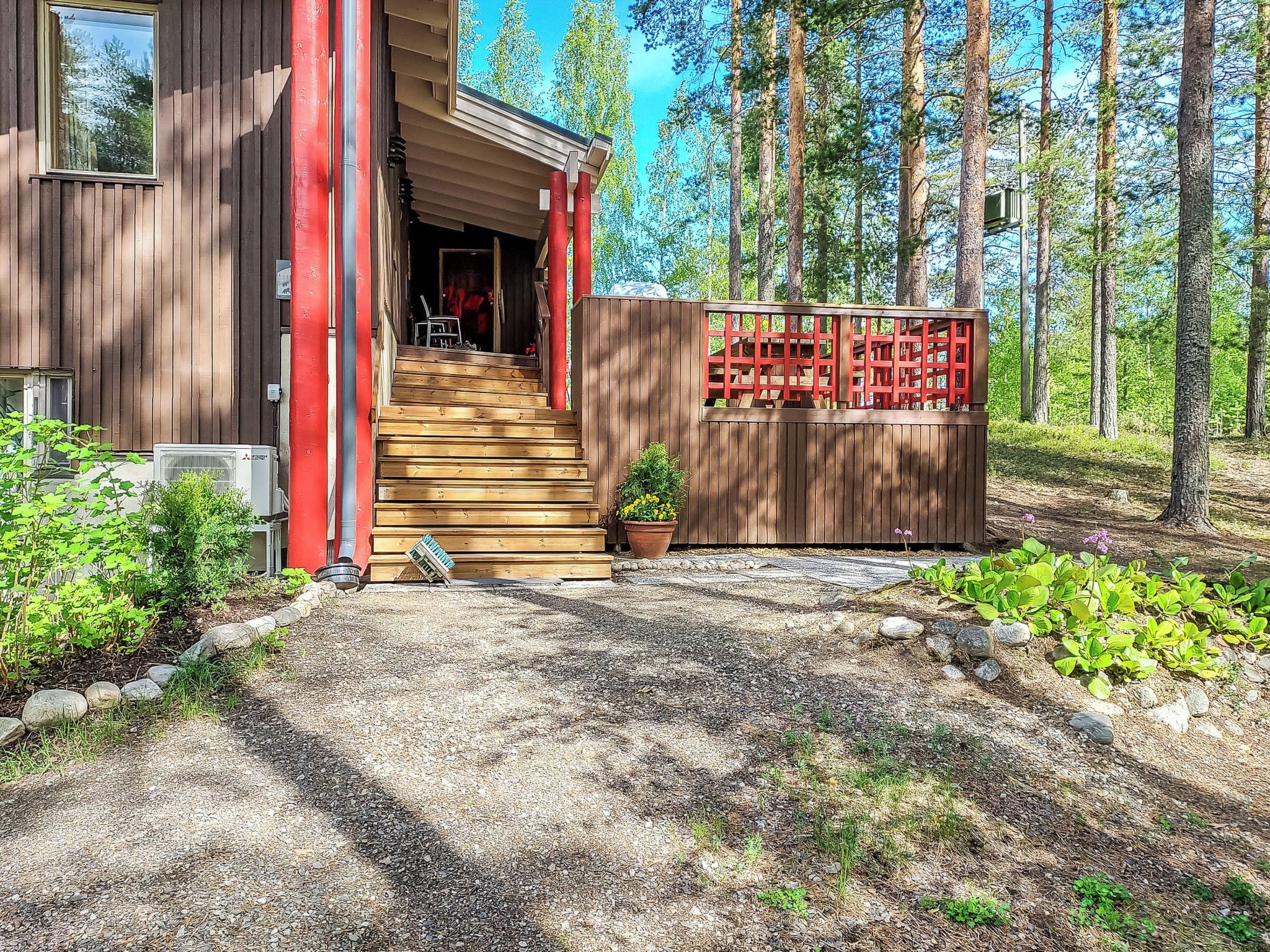 En stuga byggd av trä med en trappa som leder upp till en ingång som är skyddad av ett tak, omgiven av en skog.