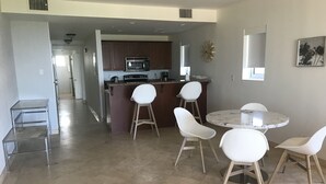 A modern kitchen with dark wooden cabinets, a stainless steel microwave, and a white island with bar stools.