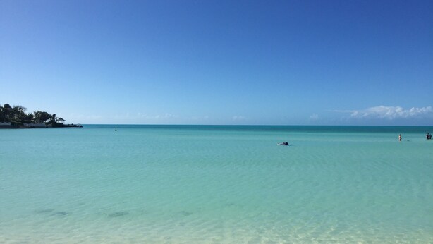 A beach with clear turquoise water and a sandy shore.