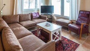 A modern living room with a sectional sofa, a single chair, a small table, and a TV.