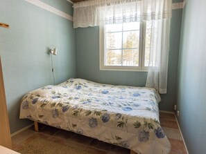 A bedroom with a bed, a window with curtains, and a wall-mounted lamp. - Ylläskankare by Interhome (Äkäslompolo)