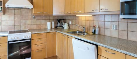 A kitchen with wooden cabinets, a stove, a dishwasher, and a microwave.