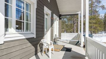 A covered porch with a table and chairs, a doormat, and a wooden bench.