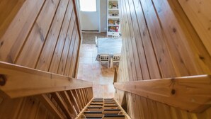 A wooden staircase with a view of a room with a bookshelf and a table.