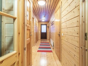 A wooden hallway with a striped rug, wooden doors, and a ceiling light.