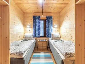 A cabin with two single beds, a small table, and a window with curtains.