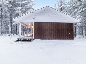 A snow-covered building with a large garage door and a covered porch area.